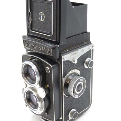 A vintage Yashica-Mat twin-lens reflex camera with a side knob and open viewfinder.