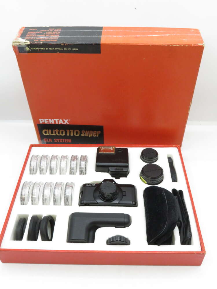 IMG_3164 Pentax auto 110 super SLR camera set with accessories, including lenses and flash, in an open red box.