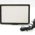 Rectangular LED light panel with a black frame, accompanied by a power adapter with a plug.