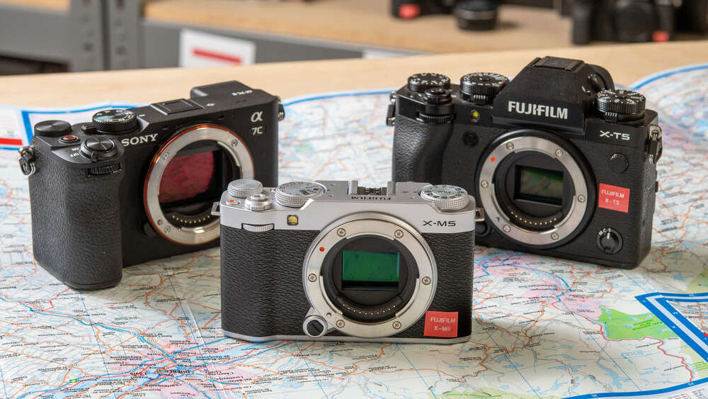 Three interchangeable-lens cameras from Sony and Fujifilm are displayed on a map, with visible lens mounts.