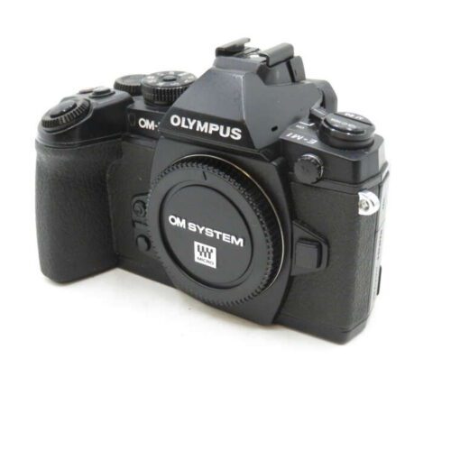 A black Olympus OM System camera with a textured grip and multiple control dials.