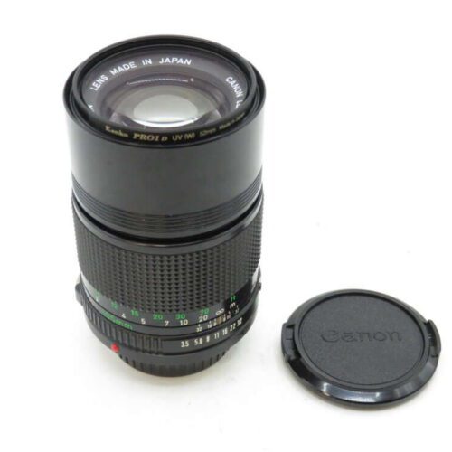 A Canon camera lens with a textured focus ring, marked "Lens Made in Japan," alongside a lens cap.