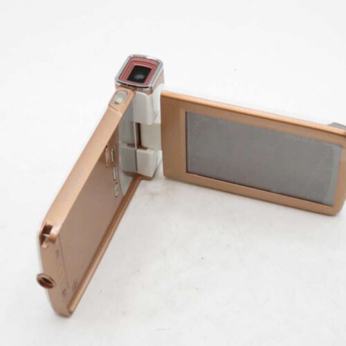 A gold digital camera with a flip-out screen and swivel lens on a white surface.
