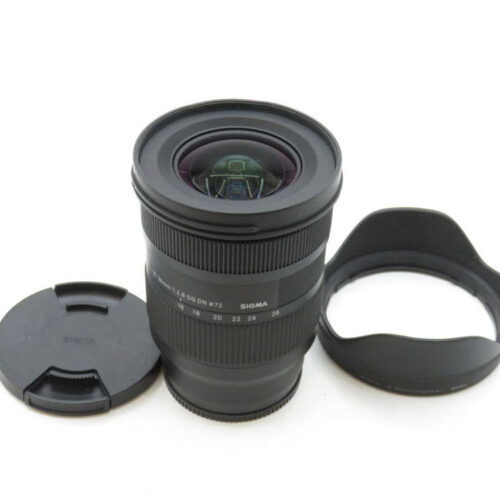 A wide-angle Sigma camera lens with a detached lens cap and hood placed nearby.