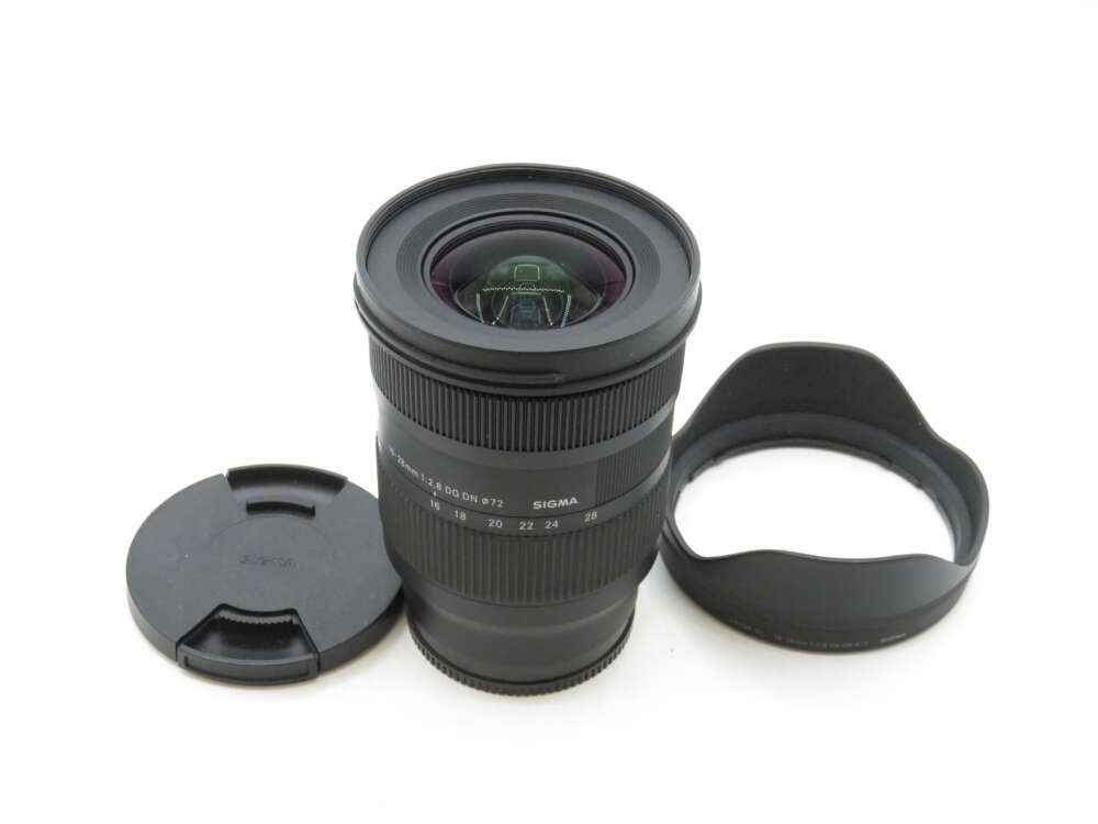IMG_3370 A wide-angle Sigma camera lens with a detached lens cap and hood placed nearby.