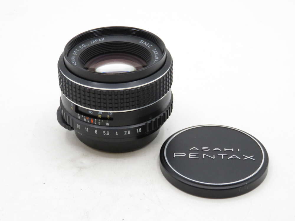 IMG_3423 A vintage Asahi Pentax camera lens with its cap, featuring detailed aperture markings.
