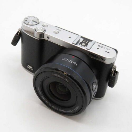 A compact digital camera with a large lens, silver and black body, and visible controls on top.