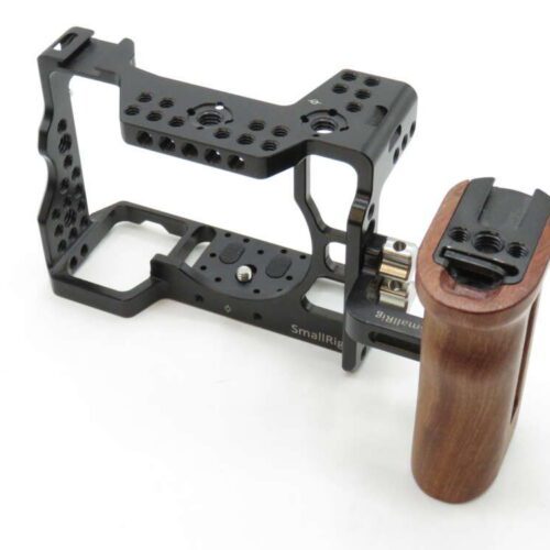 A camera cage with a wooden handle, featuring multiple attachment points, designed for stabilising and customising camera rigs.