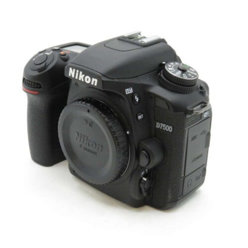 Black Nikon D7500 DSLR camera body with lens cap, featuring control dials and a textured grip.