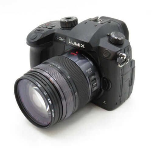 A black Lumix GH5 camera with a lens attached, featuring various buttons and dials on the top.