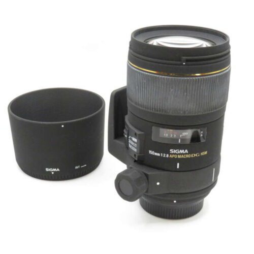 A Sigma 150mm camera lens with a protective lens hood placed beside it, both on a white background.