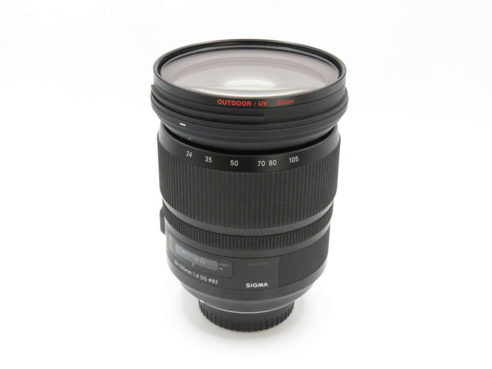IMG_3620 A Sigma camera lens with visible distance markings and a UV filter attached.