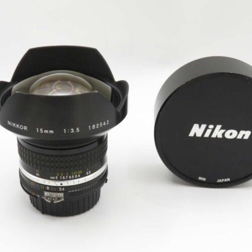 A Nikon 15mm f/3.5 camera lens with cap, featuring a wide-angle design and visible focus and aperture rings.