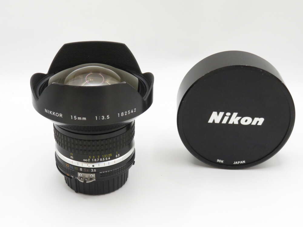 IMG_3626 A Nikon 15mm f/3.5 camera lens with cap, featuring a wide-angle design and visible focus and aperture rings.