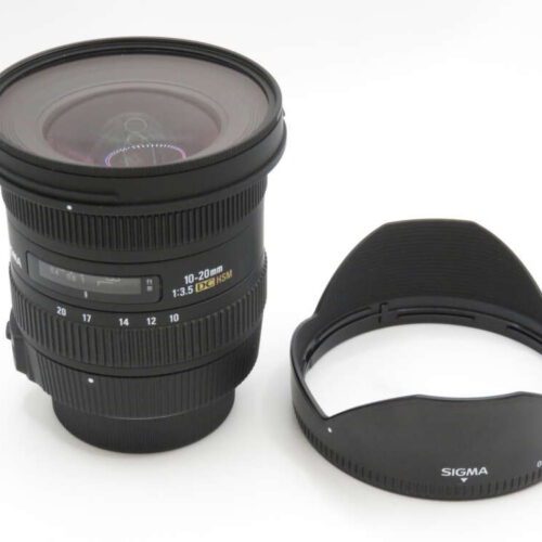 A Sigma 10-20mm f/3.5 EX DC HSM lens with a separate lens hood placed beside it.