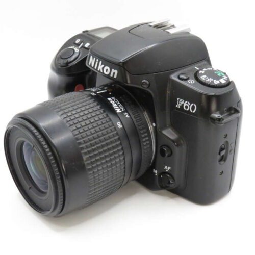 A Nikon F60 film camera with a detachable zoom lens, showing various buttons and a mode dial.