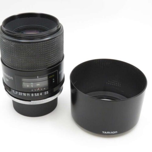 Tamron camera lens with hood placed beside it on a white surface.