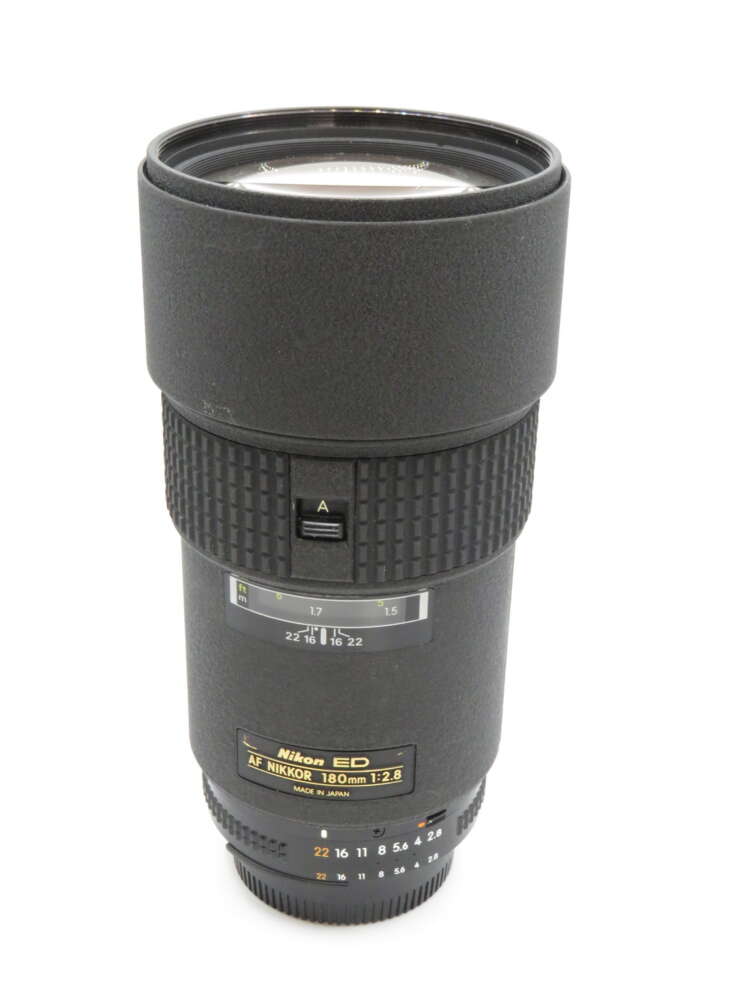 IMG_3676 A Nikon AF Nikkor 180mm f/2.8 camera lens with a textured exterior and various control dials.