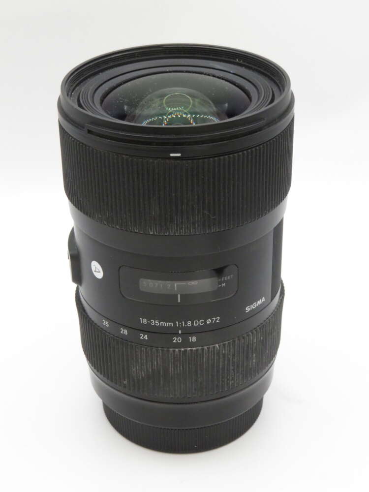 IMG_3692 A Sigma 18-35mm f/1.8 DC HSM camera lens with focus and zoom rings, shown vertically on a plain background.