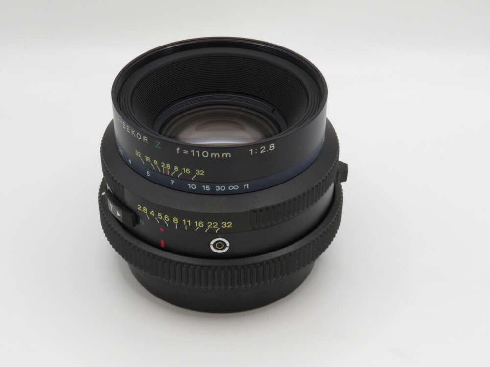 IMG_3702 A black camera lens with a focal length of 110mm and an aperture of f/2.8, featuring distance and aperture markings.