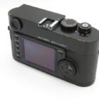 Rear view of a black Leica camera showing a large display, control buttons, and a textured grip.