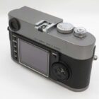 A silver and black digital camera with a screen and control buttons on the back, labelled "Leica Camera Made in Germany".