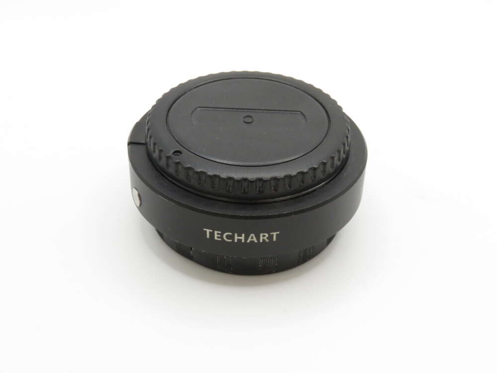 IMG_3723 A black Techart camera lens adapter with a focus ring, viewed against a plain white background.