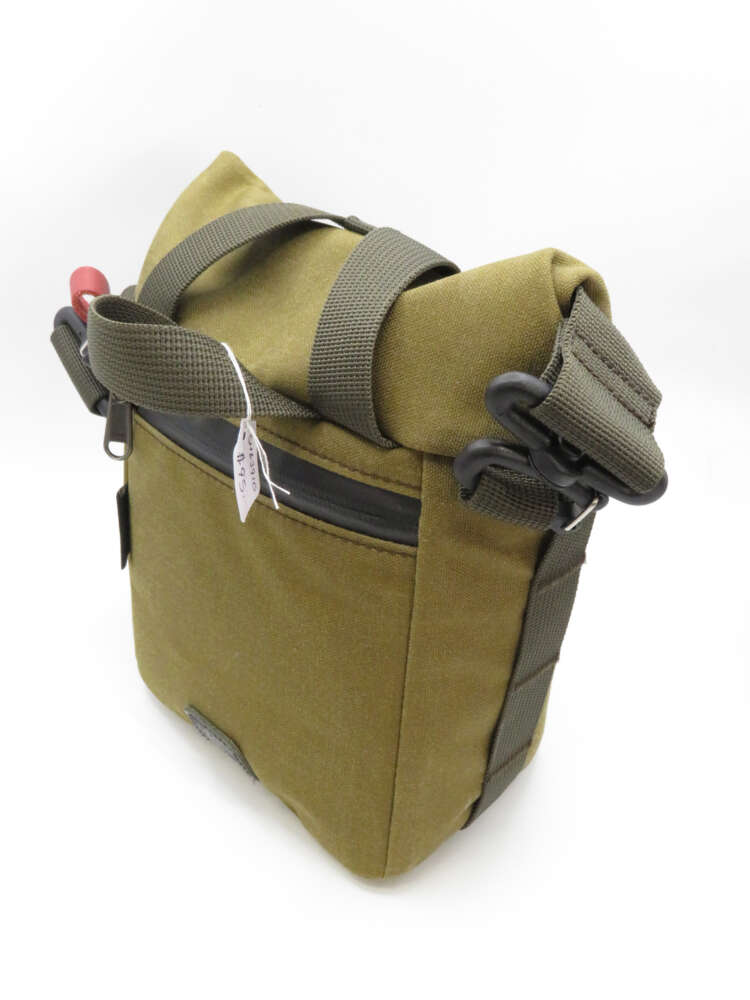 A green canvas shoulder bag with a roll-top closure and adjustable dark green straps, featuring a zippered front pocket.