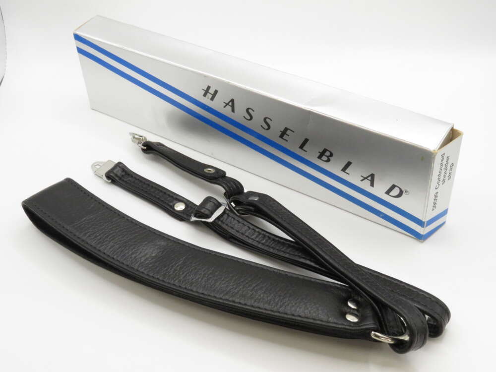 IMG_3766 A black Hasselblad camera strap lies beside its silver and blue box packaging.