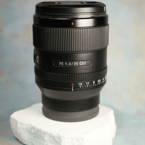 A black camera lens with detailed markings on a white textured base against a soft blue and beige background.