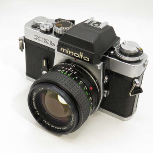 A vintage Minolta XE-1 SLR camera with a large lens and black-and-silver body.