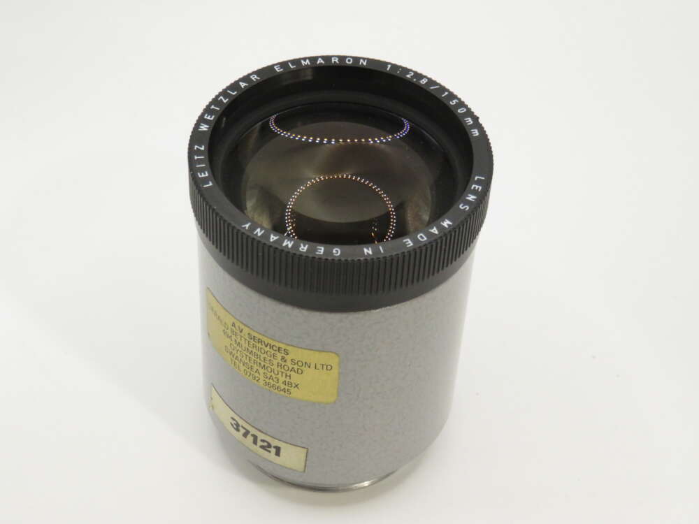 IMG_3882 A grey Leitz Wetzlar Elmaron projector lens with a black rim, displaying engraved specifications and a label with numbers.