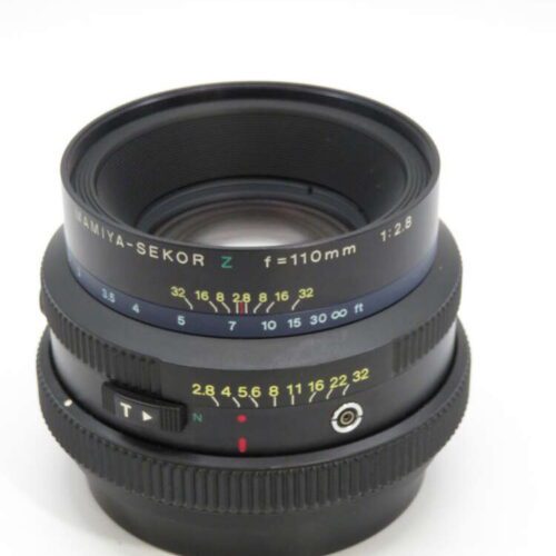 A Mamiya-Sekor camera lens with focal length 110mm and aperture 1:2.8, marked with a focus scale and depth of field indicators.