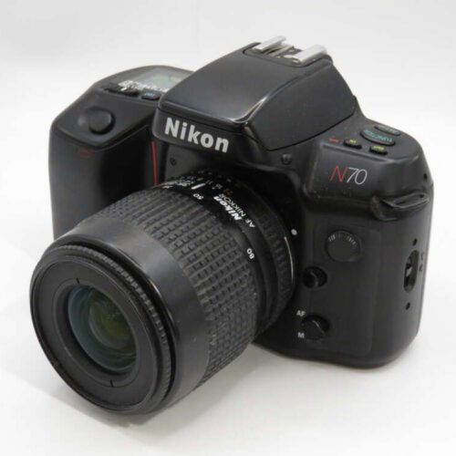 A Nikon N70 camera with a zoom lens attached, featuring various control buttons and a visible LCD screen on the top panel.
