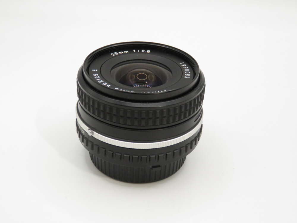 IMG_3915 A black camera lens with white text indicating "28mm 1:2.8" and textured grip rings on a plain white background.