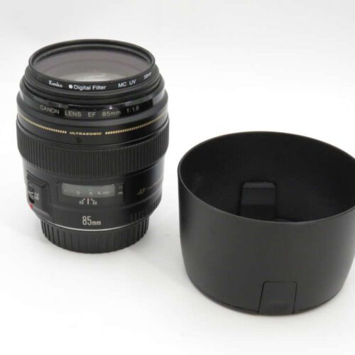 Canon EF 85mm f/1.8 lens with a lens hood placed beside it on a plain background.