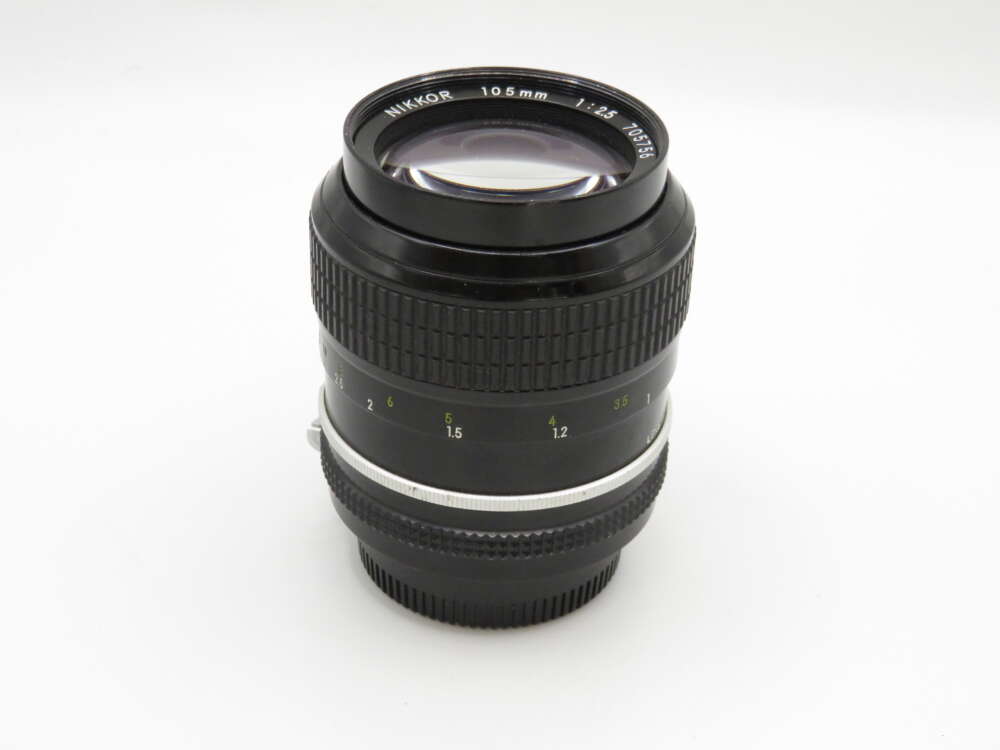 IMG_3952 A Nikon Nikkor 105mm f/2.5 camera lens with aperture and focus rings visible.