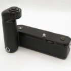 A black camera grip with a textured surface and control buttons, designed for attachment to a camera body.