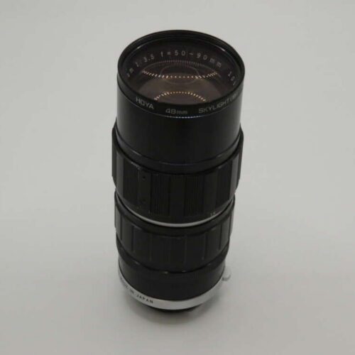 A vintage telephoto camera lens with a Hoya Skylight filter, displaying markings 1:3.5 f=135mm, 90mm Japan, on a plain backdrop.
