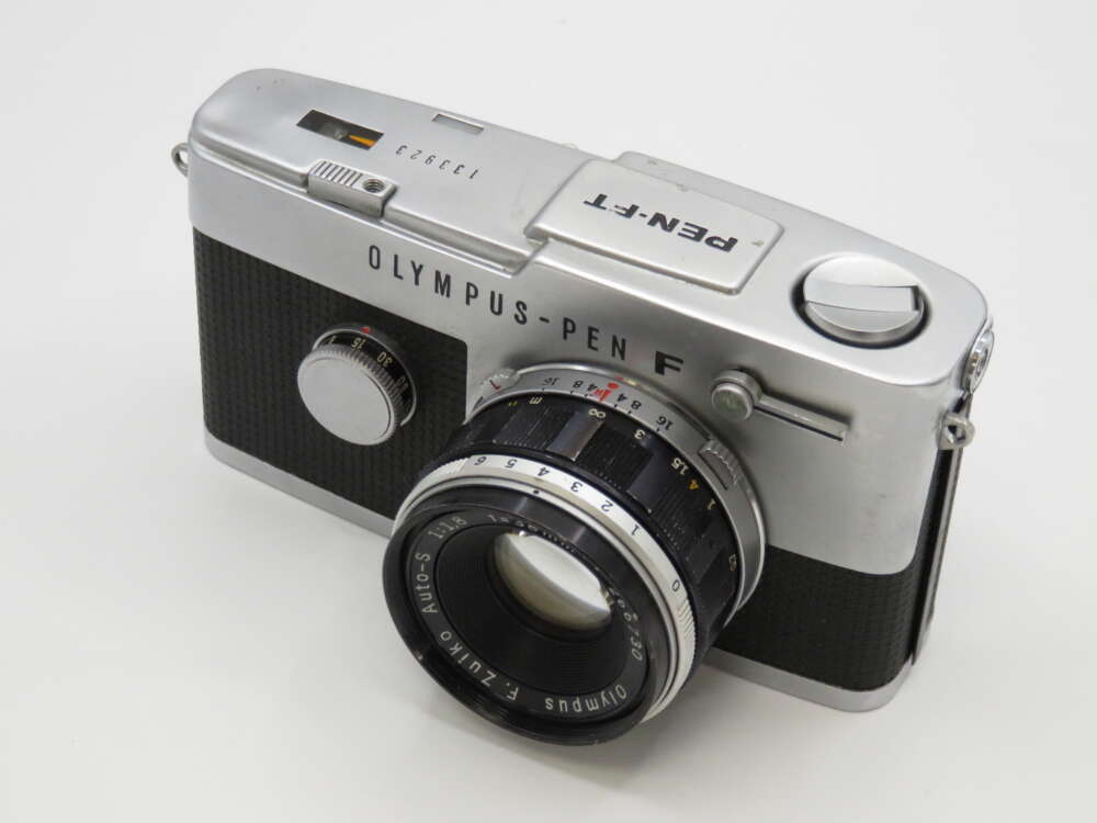 IMG_3975 A vintage Olympus Pen F 35mm film camera with a silver body and a black textured grip.