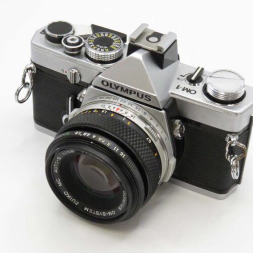A vintage Olympus OM-1 camera with a sleek design and leather grip, featuring a lens and visible dials.