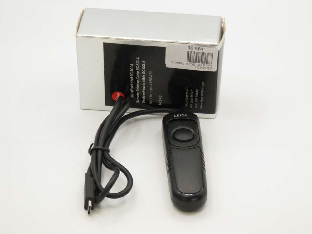 IMG_4001 Remote control with a black casing and a cable next to a white box labeled "Leica."