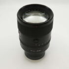 Camera lens with "FE 1.8/135 GM" marking, featuring a sleek black design on a plain white background.