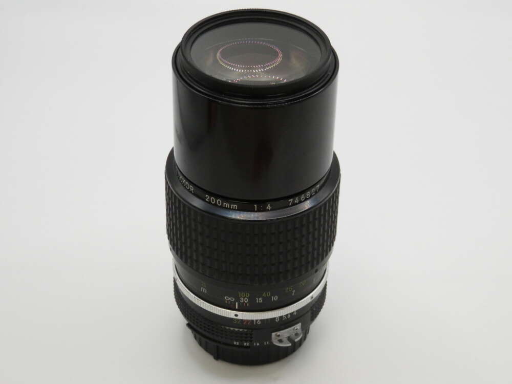 IMG_4017 A telephoto camera lens with a textured grip and focus markings on a white background.