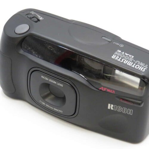 A Ricoh film camera with a textured black body, zoom lens, and flash compartment.