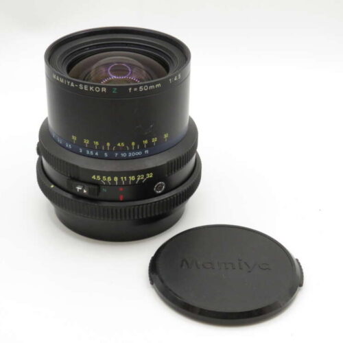 A Mamiya-Sekor Z 50mm f/4.5 camera lens with a detached cap placed nearby.