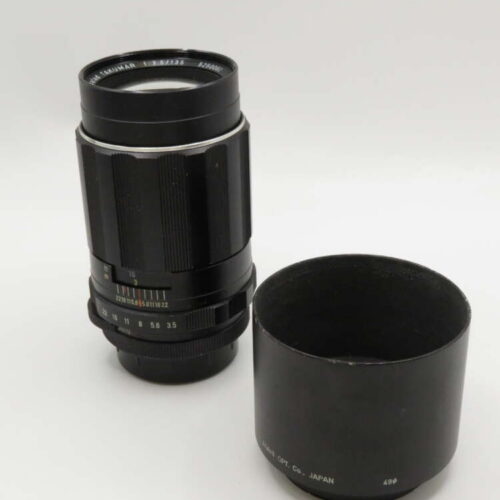 A black camera lens with a detachable hood placed beside it on a white background.