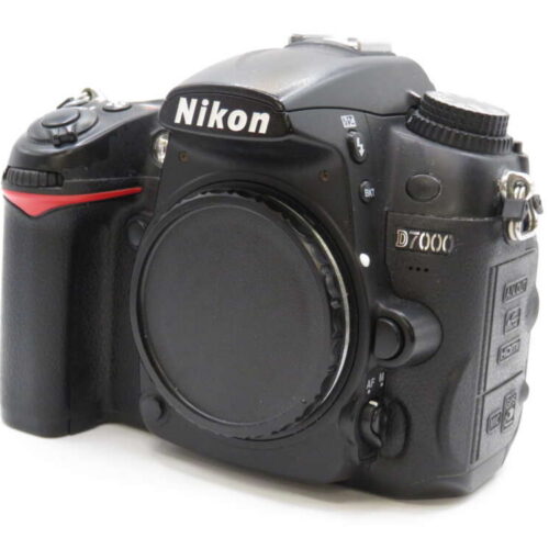 A Nikon D7000 DSLR camera body with a black finish, featuring various control buttons and a lens mount cover.