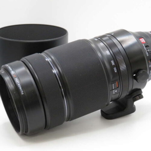A large black camera zoom lens with a tripod mount is placed in front of its detached lens hood.