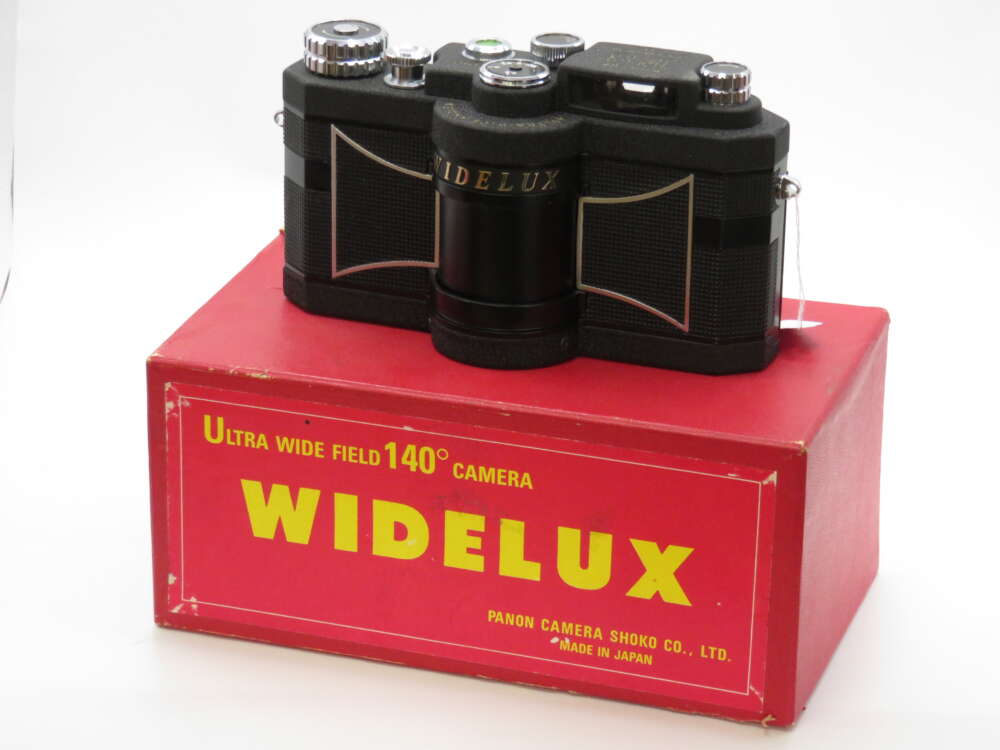 IMG_4151 A vintage Widelux panoramic camera placed on top of its red box with yellow text detailing its features.